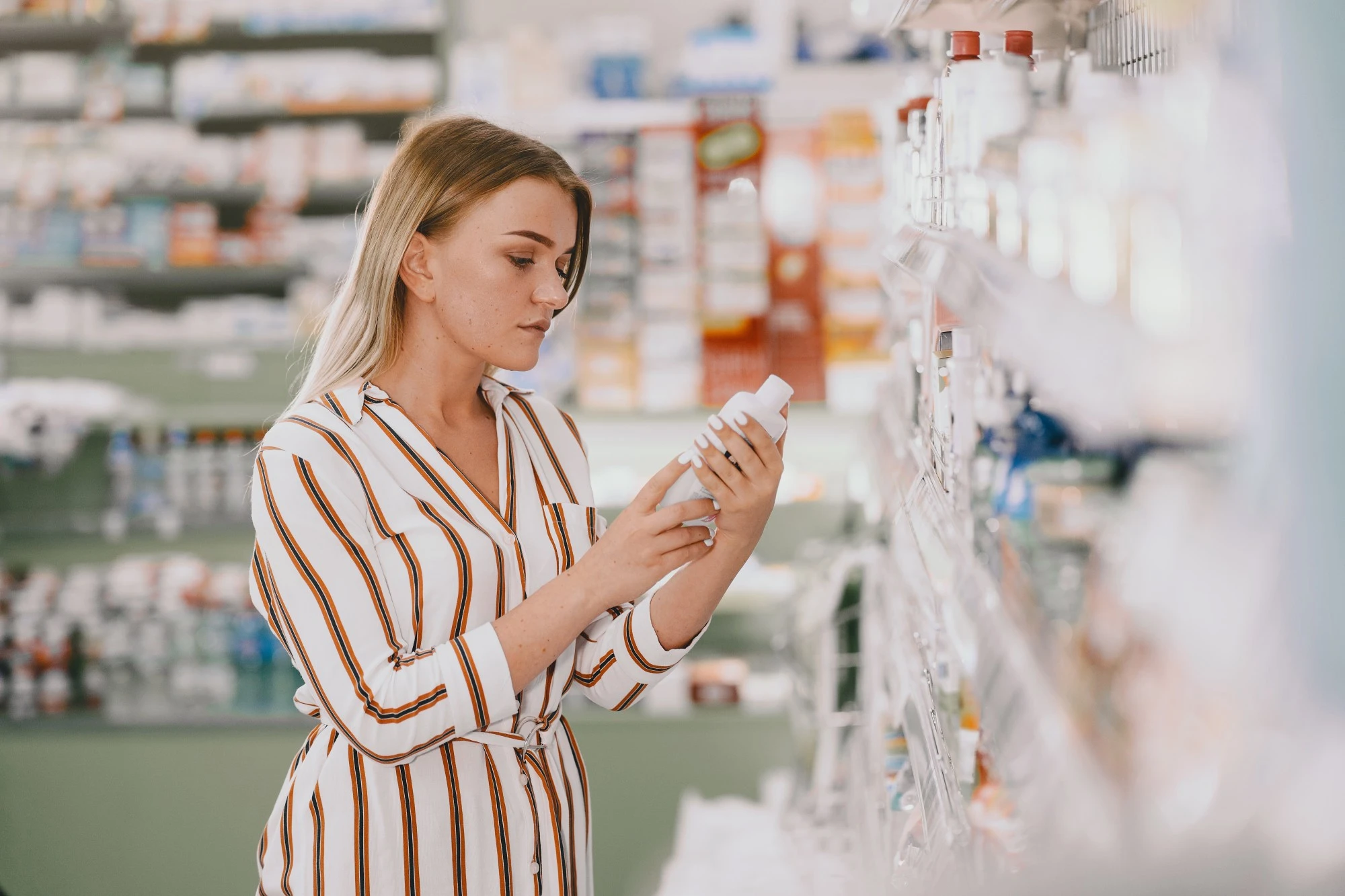 Woman reading sunscreen label while shopping in a skincare store - Zicail Beauty Woman reading sunscreen label while shopping in a skincare store - Why Does Sunscreen Pill? Stop SPF Pilling Under Makeup