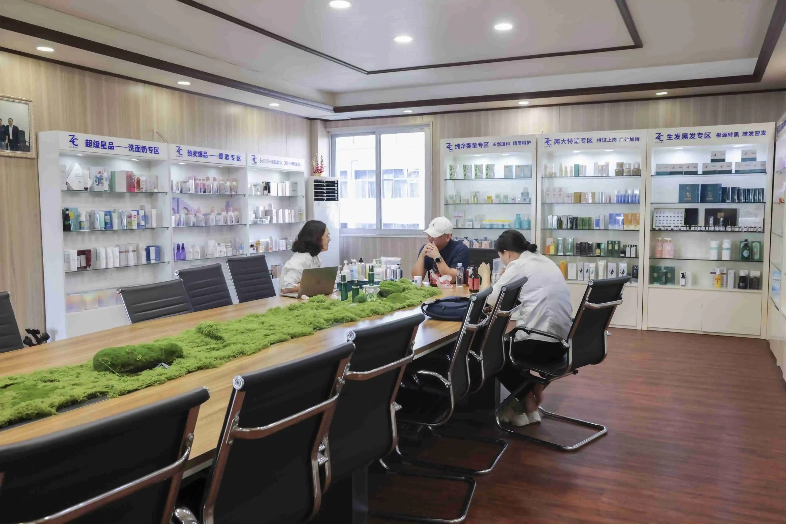 ZICAIL skincare showroom with product display shelves, meeting table, and visitors discussing cosmetic packaging and formulas. - Zicail Beauty ZICAIL skincare showroom with product display shelves, meeting table, and visitors discussing cosmetic packaging and formulas. - SPF and Barrier-Support Products Driving Early Summer Skincare Launches